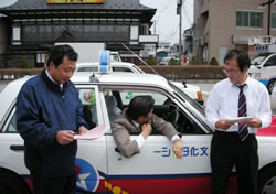 アンケートを手に乗務員と対話する赤井さん（左）＝４月１６日、青森・八戸駅