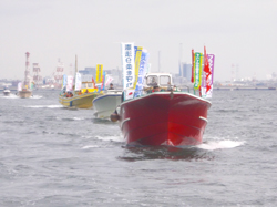 組合旗をなびかせた船で海上デモを行う参加者＝３月３日、東京湾